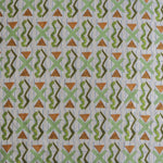 Close up of printed fabric with green squiggles, orange striped triangles, light green X marks on a broken grid in blue on a white background. 
