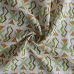 Close up of gently draped printed fabric with green squiggles, orange striped triangles, light green X marks on a broken grid in blue on a white background. 