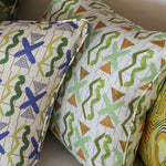 Detail of stacked throw pillows in a squiggle and x pattern in various colors. 