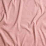 Close up of gently draped pin striped woven Indoor-Outdoor fabric in white and coral pink.