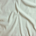 Close up of gently draped pin striped woven Indoor-Outdoor fabric in white and green