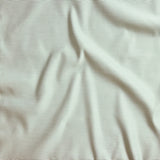 Close up of gently draped pin striped woven Indoor-Outdoor fabric in white and green