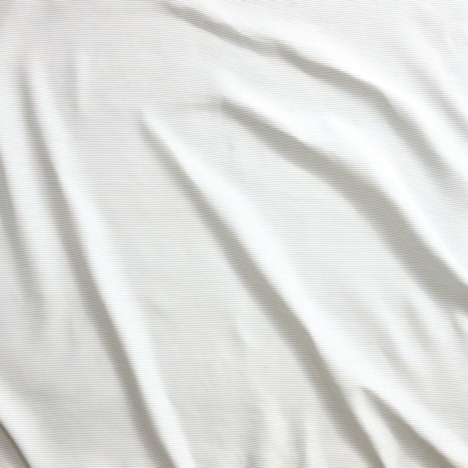 Close up of gently draped pin striped woven Indoor-Outdoor fabric in white.