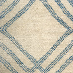 Close-up of a textured rug with blue geometric pattern on beige background