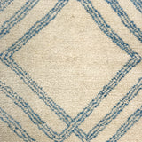 Close-up of a textured rug with blue geometric pattern on beige background