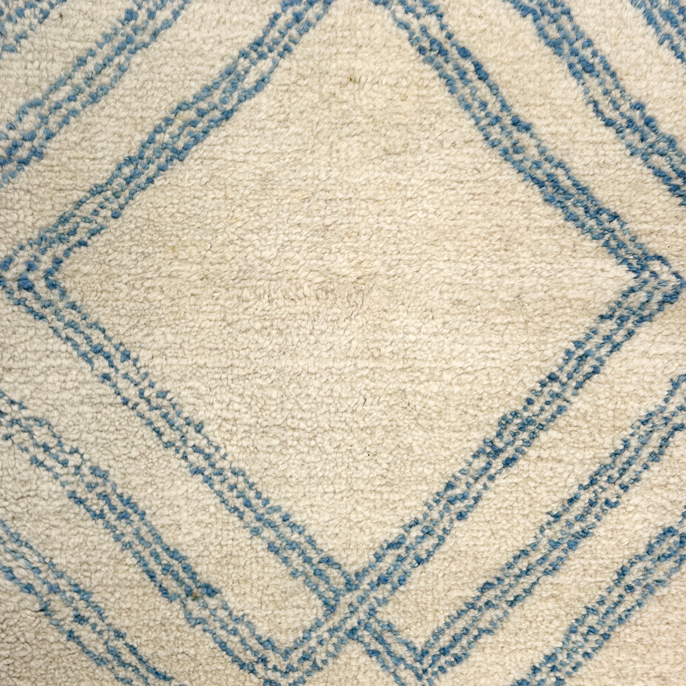 Close-up of a textured rug with blue geometric pattern on beige background