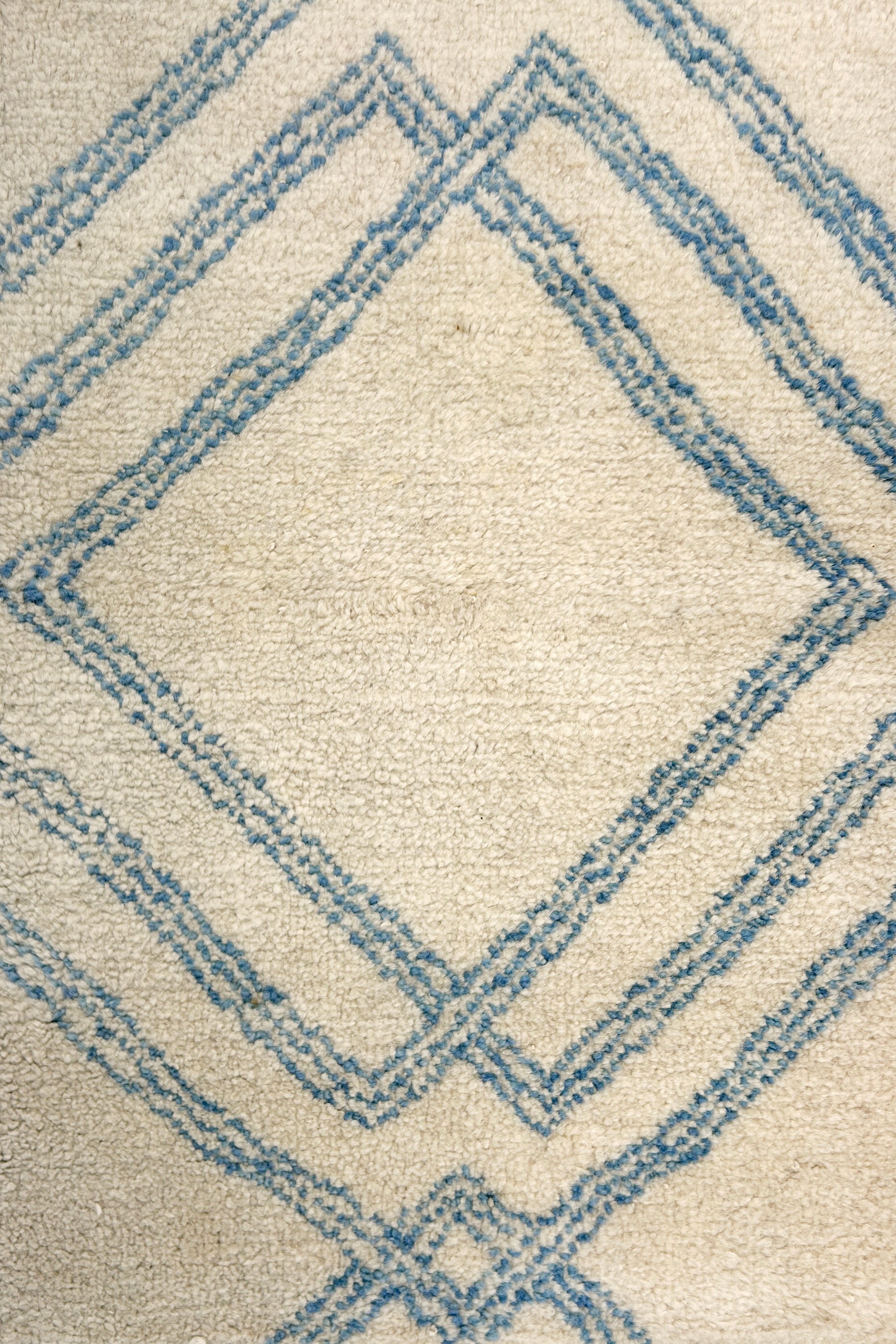 Close-up of a textured rug with blue geometric pattern on beige background