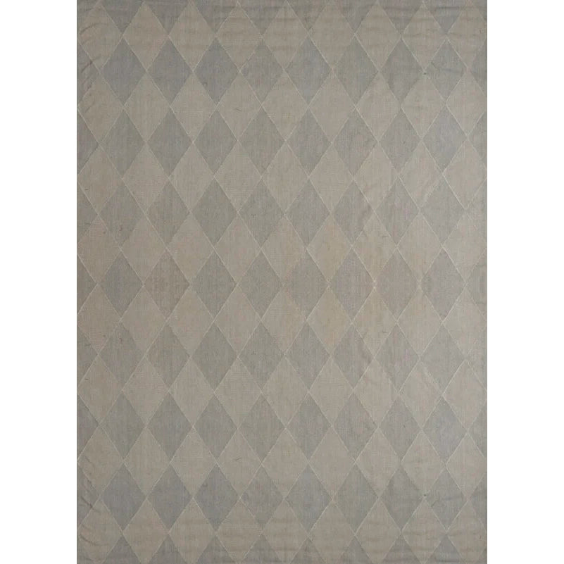 An area rug featuring a classic harlequin diamond pattern in shades of gray and beige.
