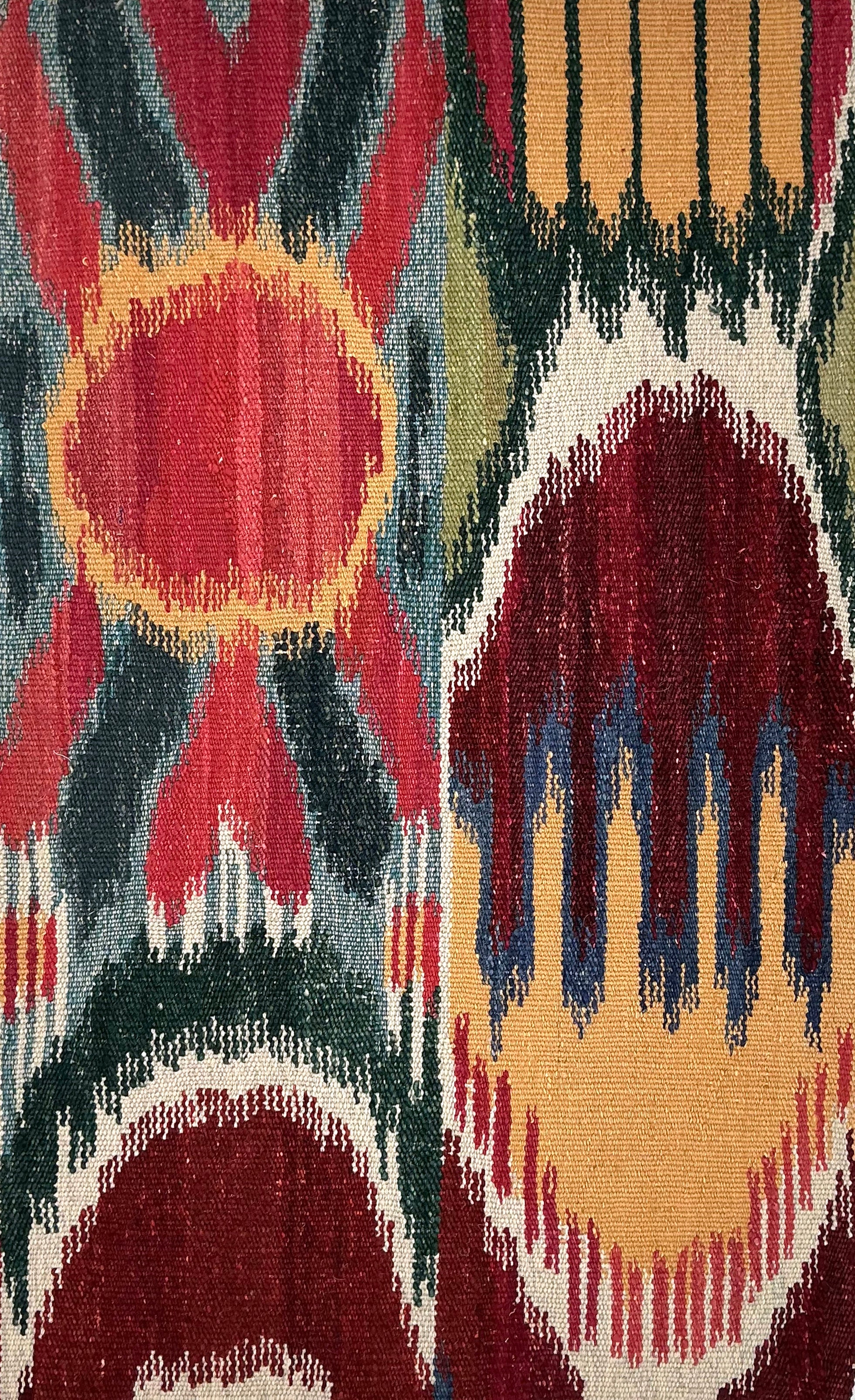 Close-up of a ikat patterned rug with geometric shapes in red, blue, and beige.