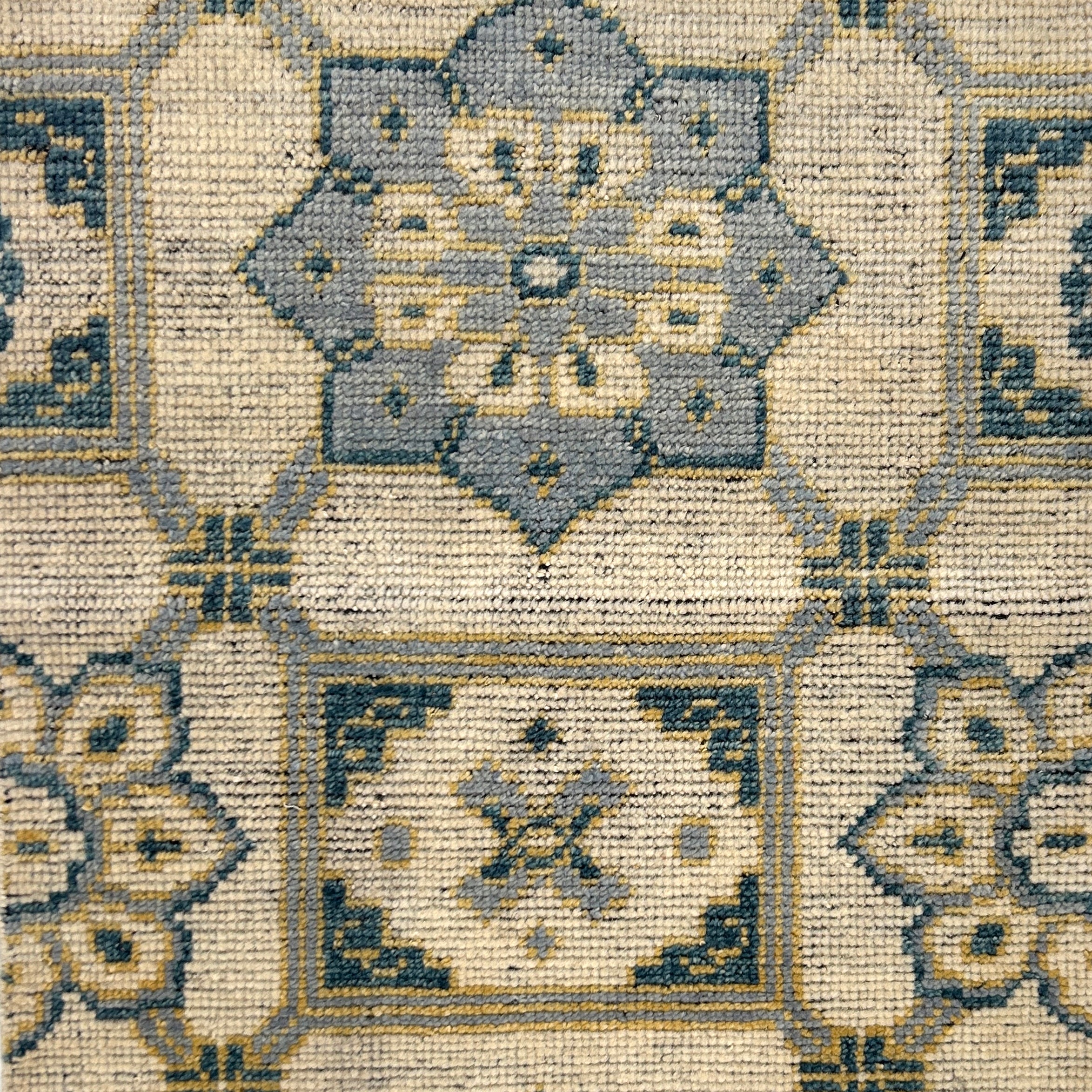 Close-up of a patterned rug with geometric designs in beige, brown, and gray.