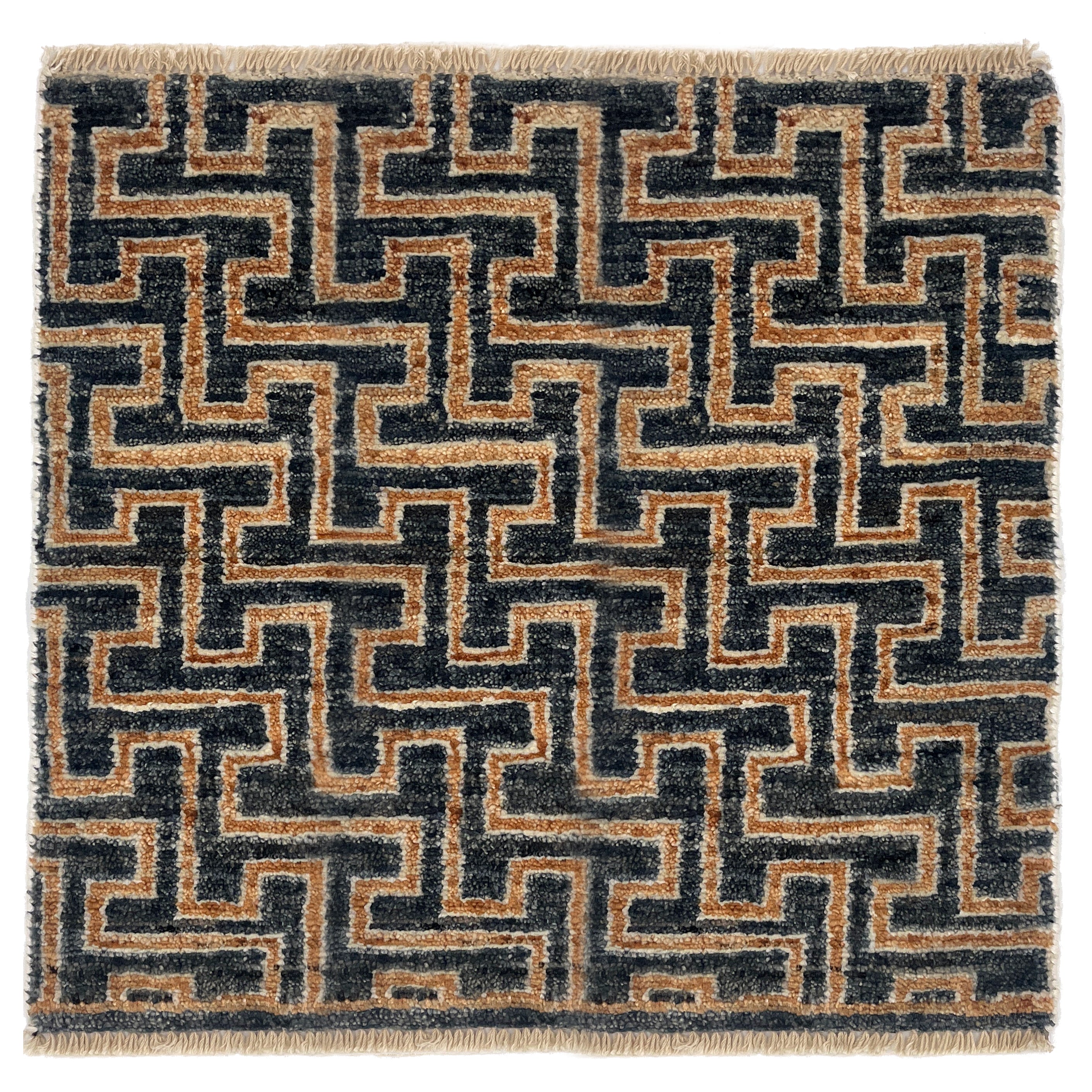 A square area rug with a geometric maze-like pattern in black and tan, finished with a fringed edge.