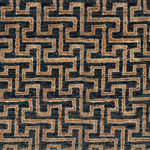 A close-up of a handknotted rug with a repeating geometric maze-like pattern in dark charcoal gray and warm tan