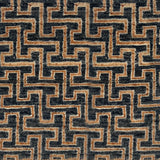A close-up of a handknotted rug with a repeating geometric maze-like pattern in dark charcoal gray and warm tan