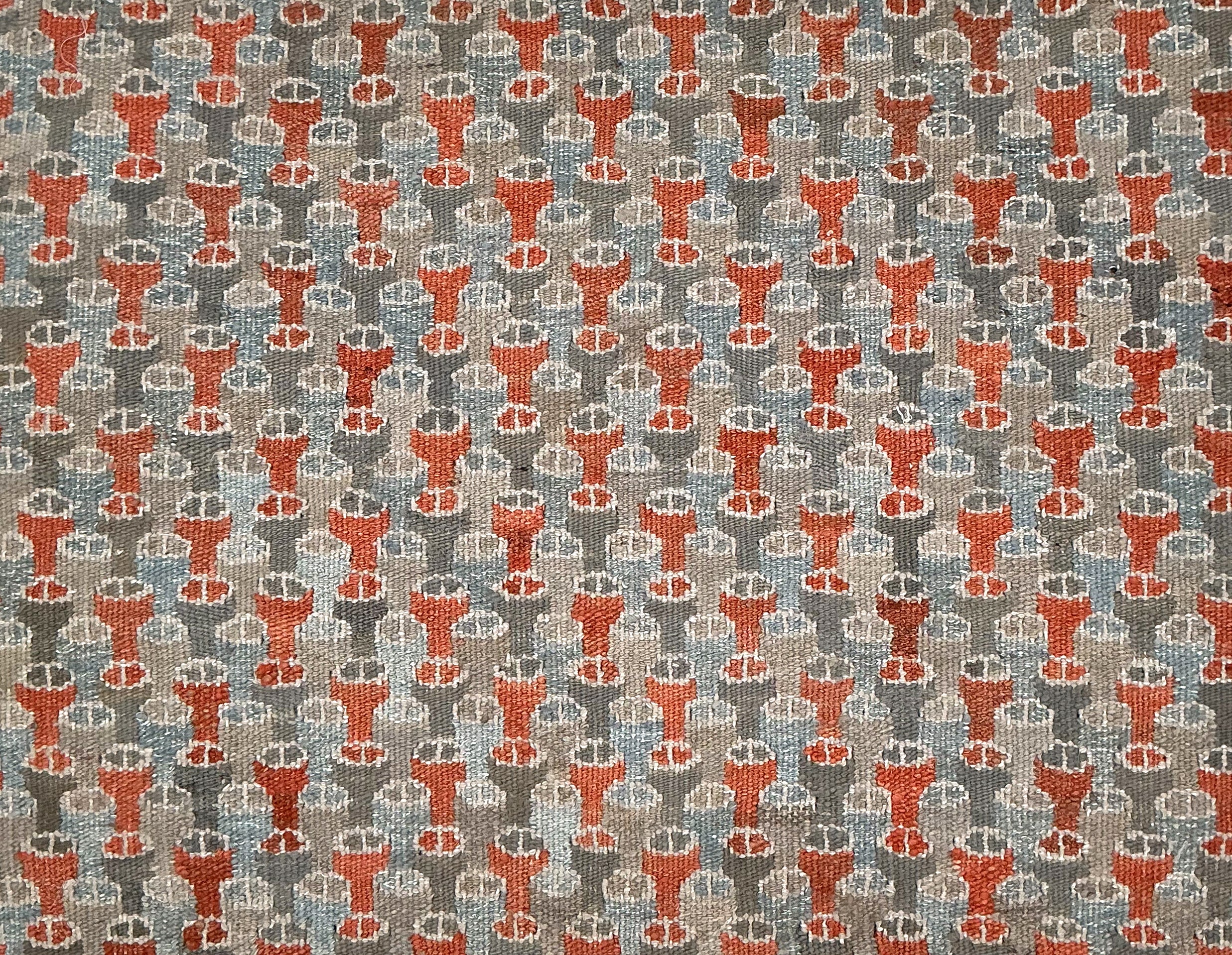 Patterned rug with red and gray design on a gray background