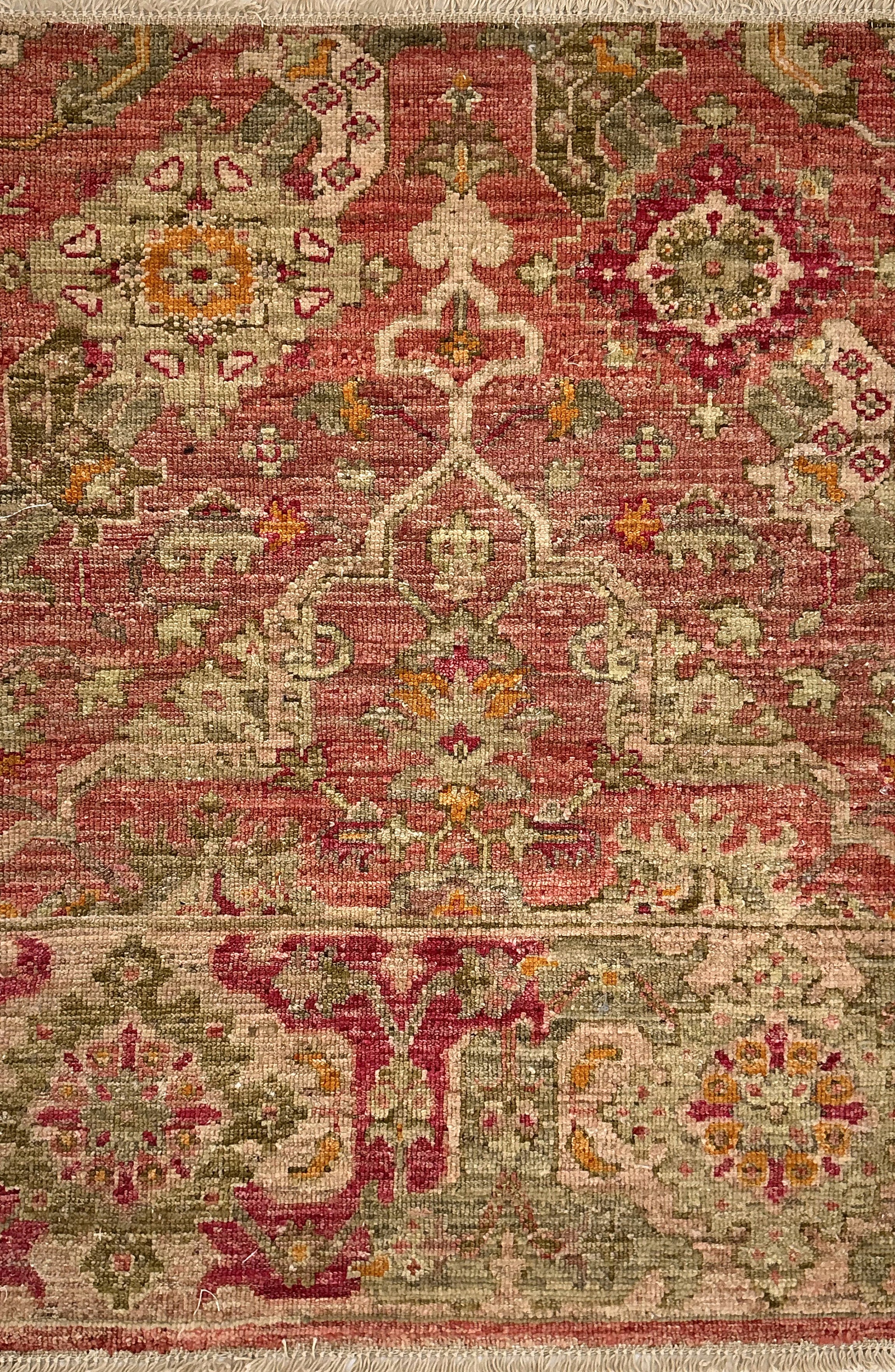 Decorative rug with intricate patterns in red, green, and beige on a plain background
