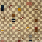 Handknotted rug in a playful checkerboard design in taupe and cream with colorful accents. 