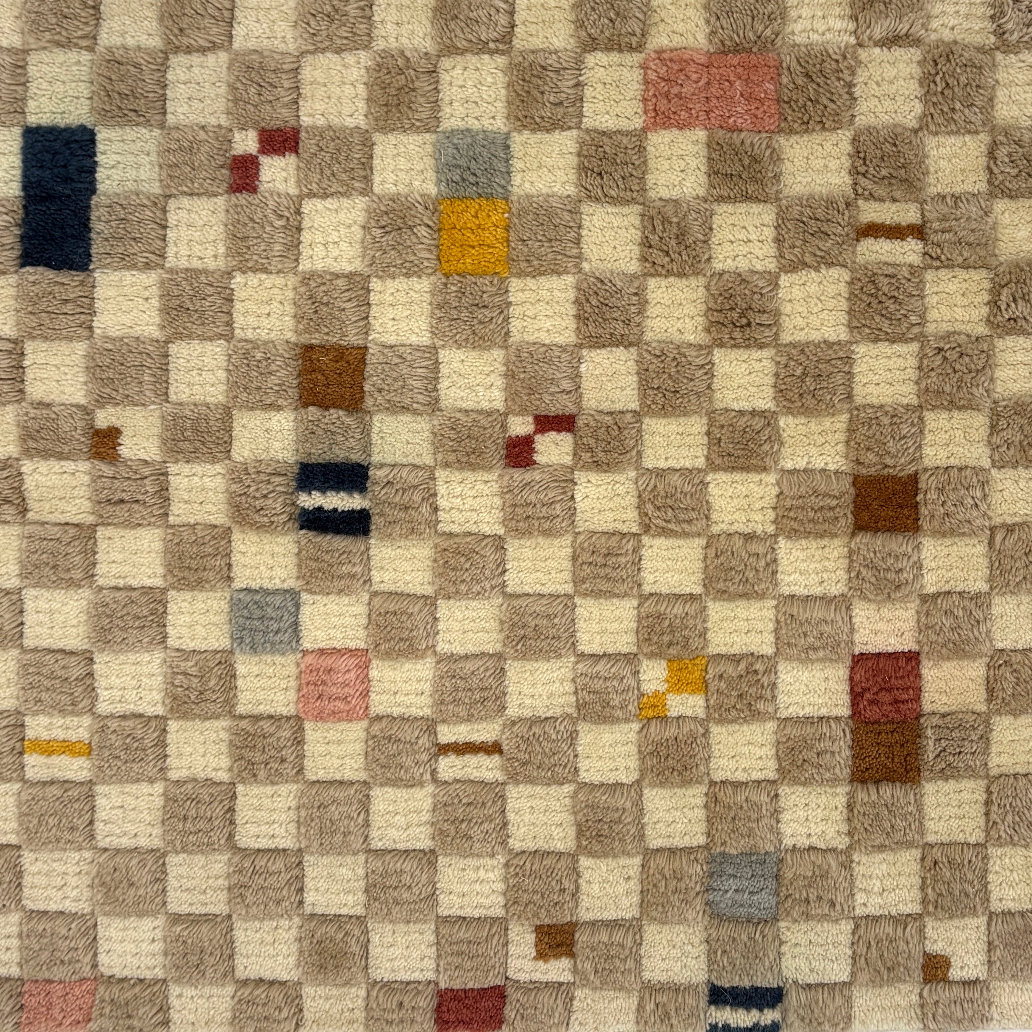 Handknotted rug in a playful checkerboard design in taupe and cream with colorful accents. 