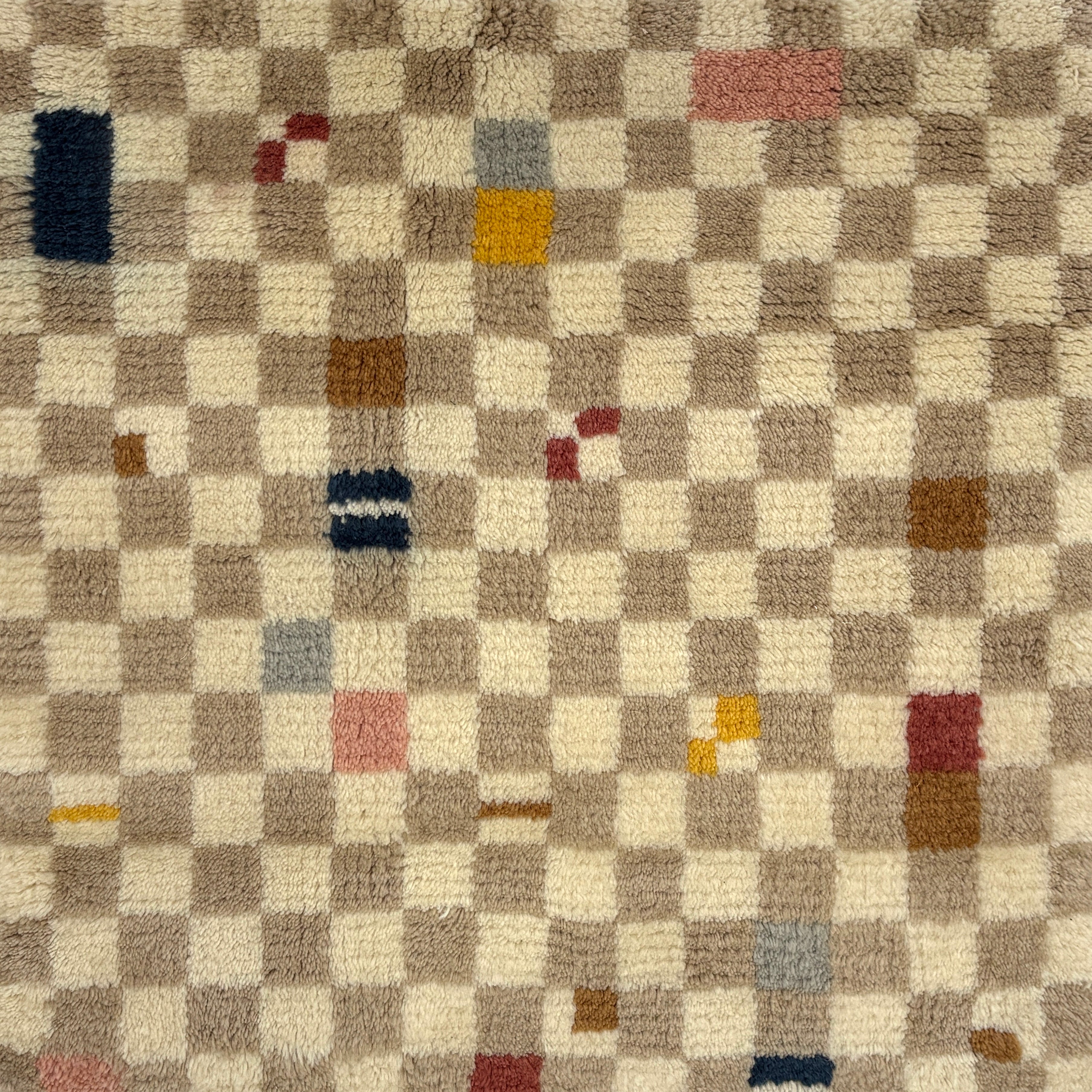 Handknotted rug in a playful checkerboard design in taupe and cream with colorful accents. 