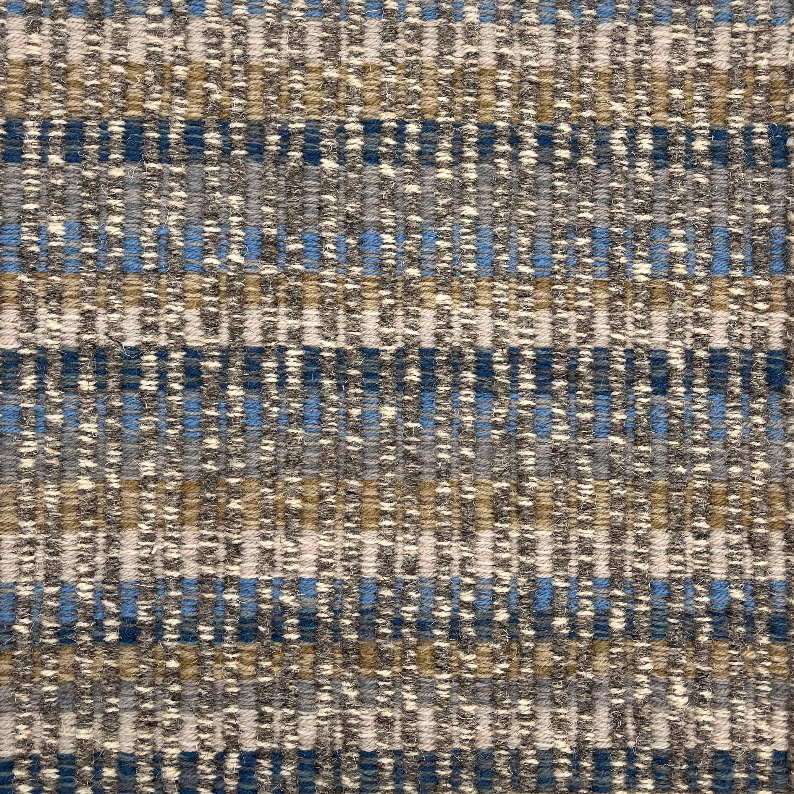 Handwoven rug detail in a textural design in blue, tan and cream