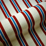 Striped fabric with red, white, and blue horizontal stripes on a beige background