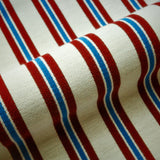 Striped fabric with red, white, and blue horizontal stripes on a beige background