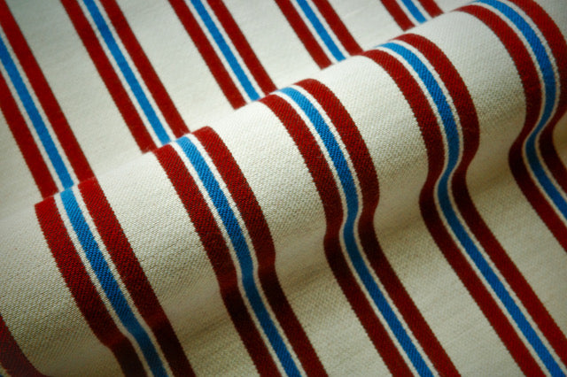Striped fabric with red, white, and blue horizontal stripes on a beige background