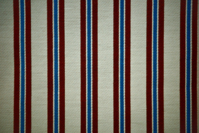 Striped fabric with red and blue vertical stripes on a beige background