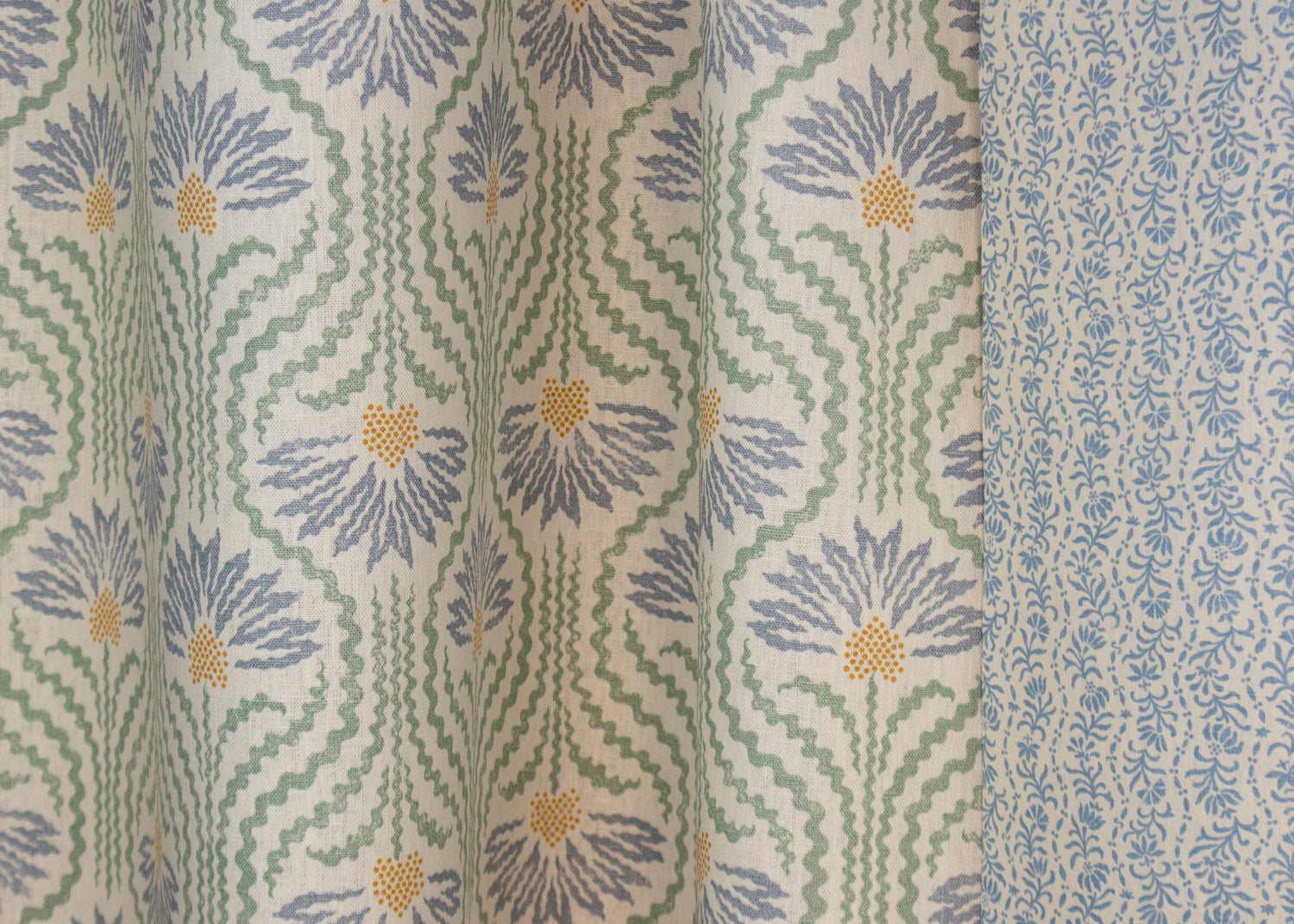 Draped printed linen in a playful dense blue and yellow with radiating green lines on a cream field. 