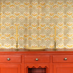 Curtain in playful yellow floral linen with an orange wooden credenza with taper candles and ceramic plate. 
