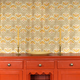 Curtain in playful yellow floral linen with an orange wooden credenza with taper candles and ceramic plate. 