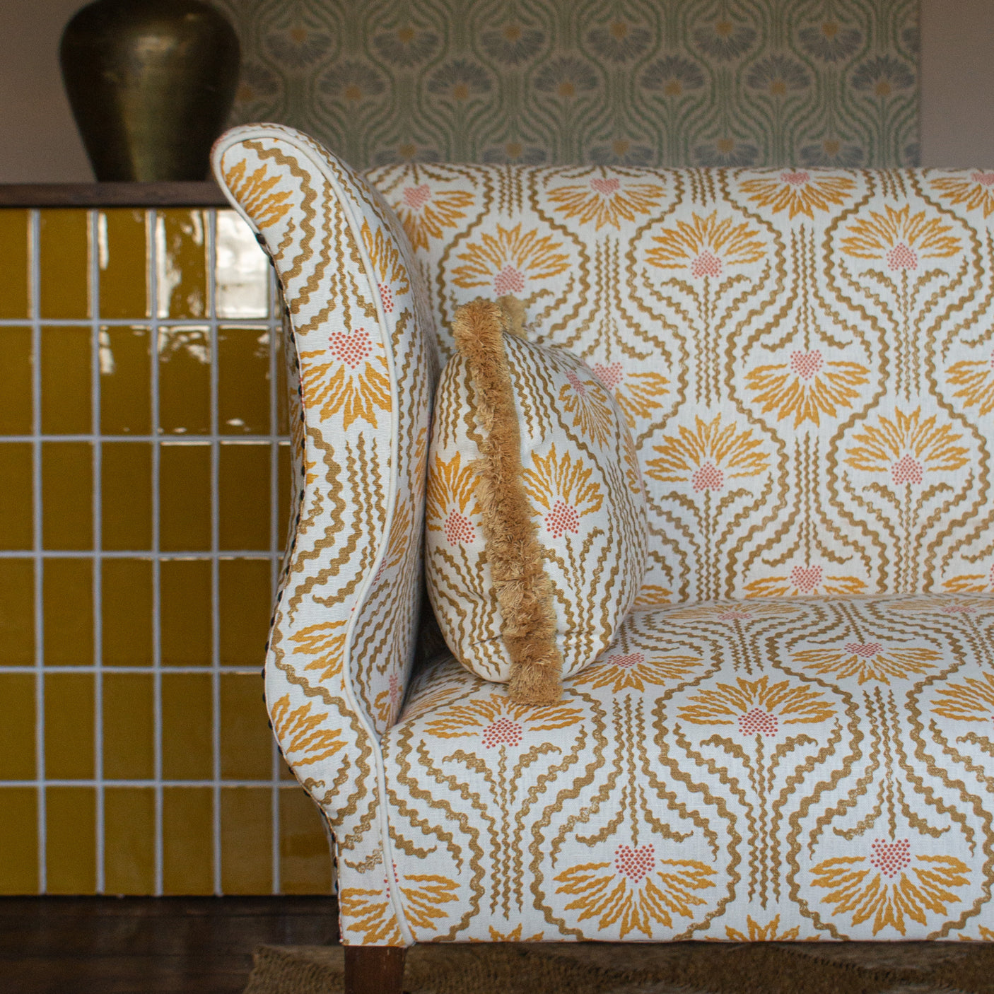 Settee upholstered in a yellow, tan and cream pattern on a dute carpet against yellow tiles. 