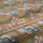 Close-up of patterned fabric with orange, green, and gray colors.