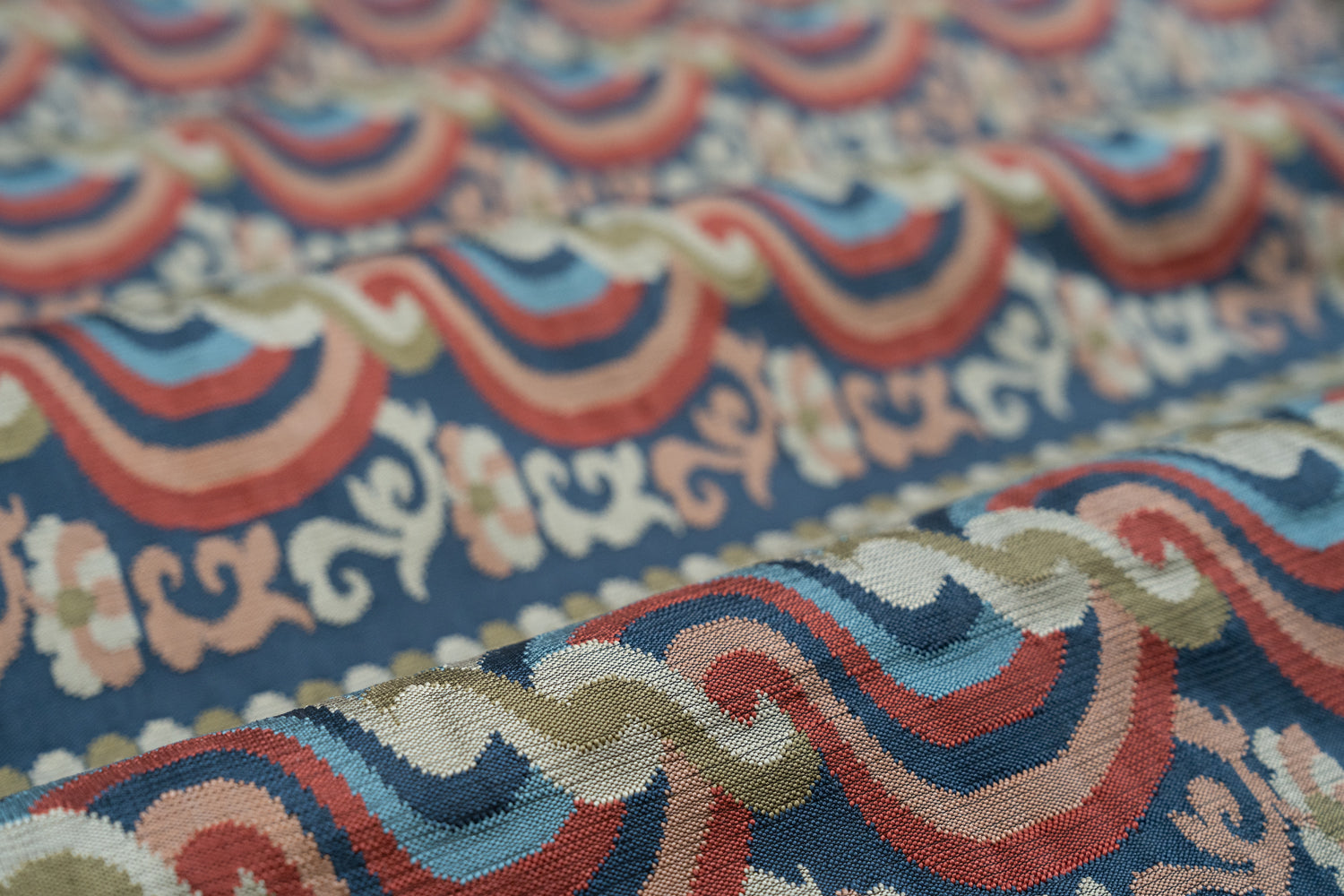Close-up of a textured fabric with red, blue and pink ornate pattern. 