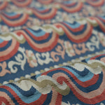 Close-up of a textured fabric with red, blue and pink ornate pattern. 