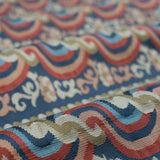 Close-up of a textured fabric with red, blue and pink ornate pattern. 