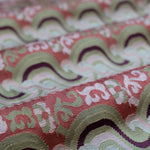 Close-up of folded handwoven silk fabric with a wavy pattern in red, green, and white.