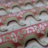 Close-up of folded handwoven silk fabric with a wavy pattern in red, green, and white.