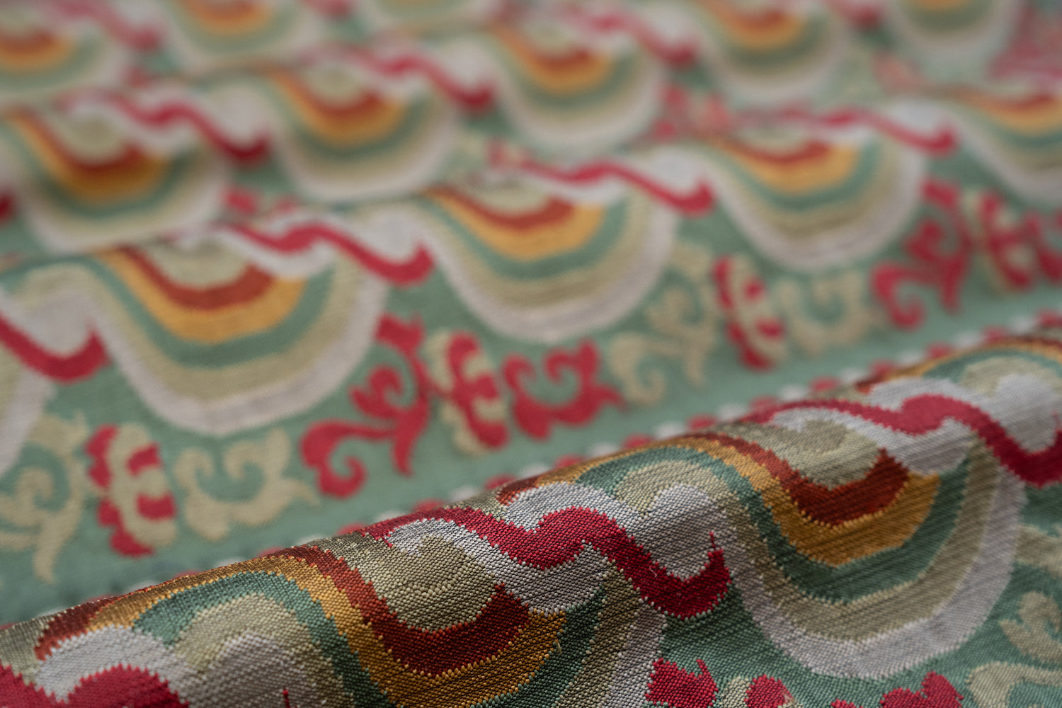 Close-up of colorful fabric with wavy red and orange pattern on a green background