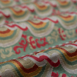 Close-up of colorful fabric with wavy red and orange pattern on a green background