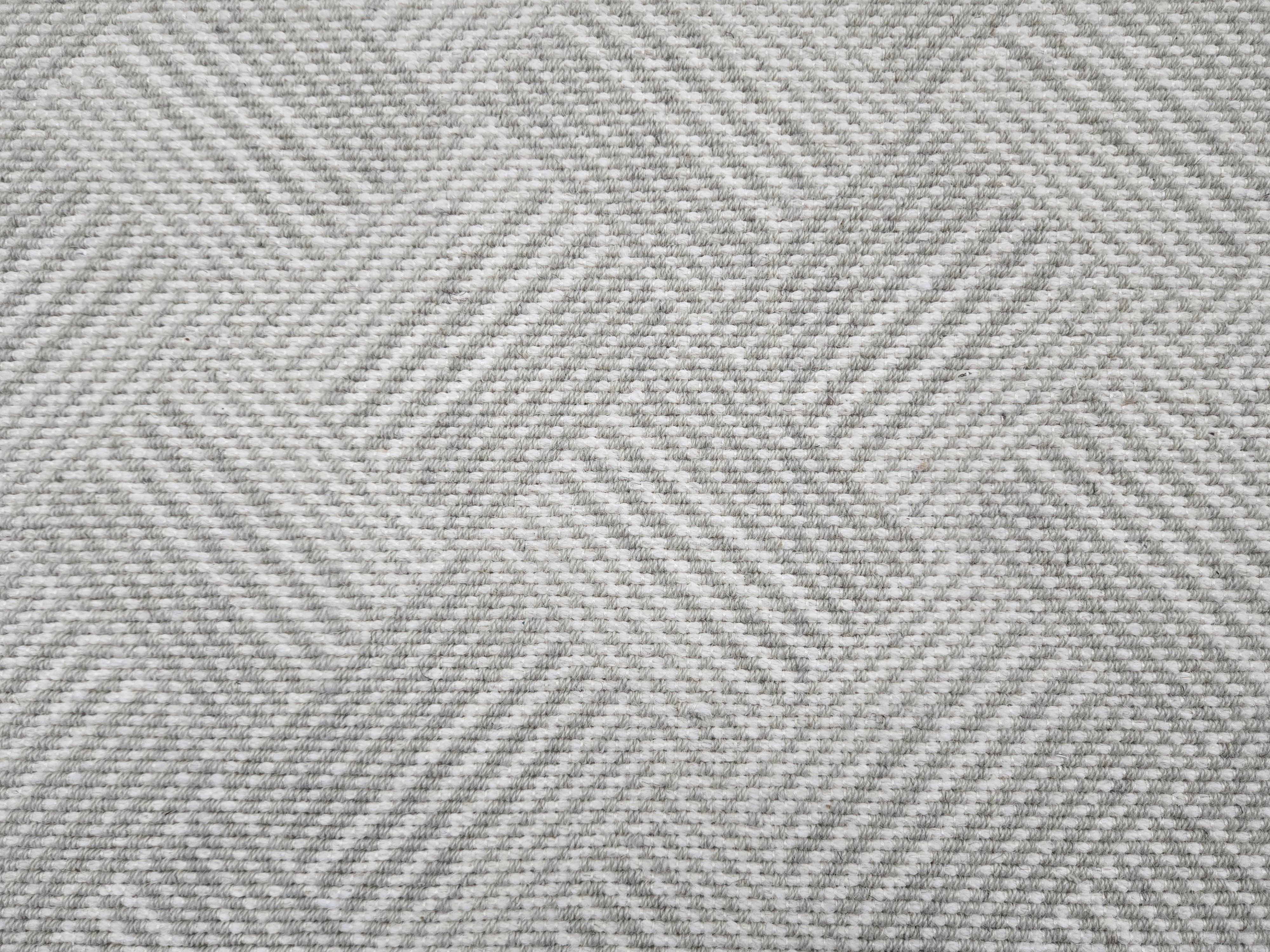 Broadloom rug sample in a diamond pattern in stripes of white and light grey.