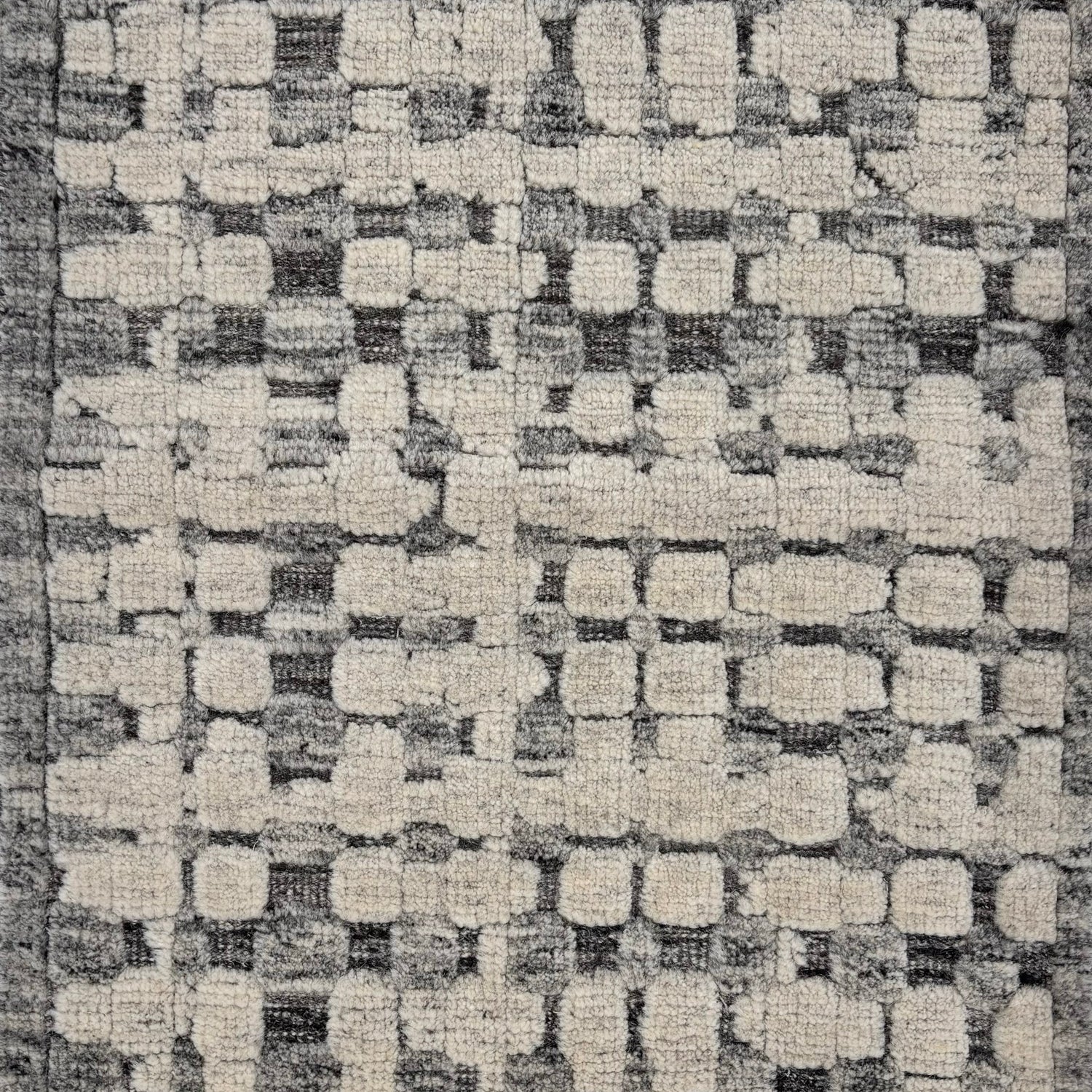 Handknotted rug sample in a textural geometric pattern in grey and ivory.