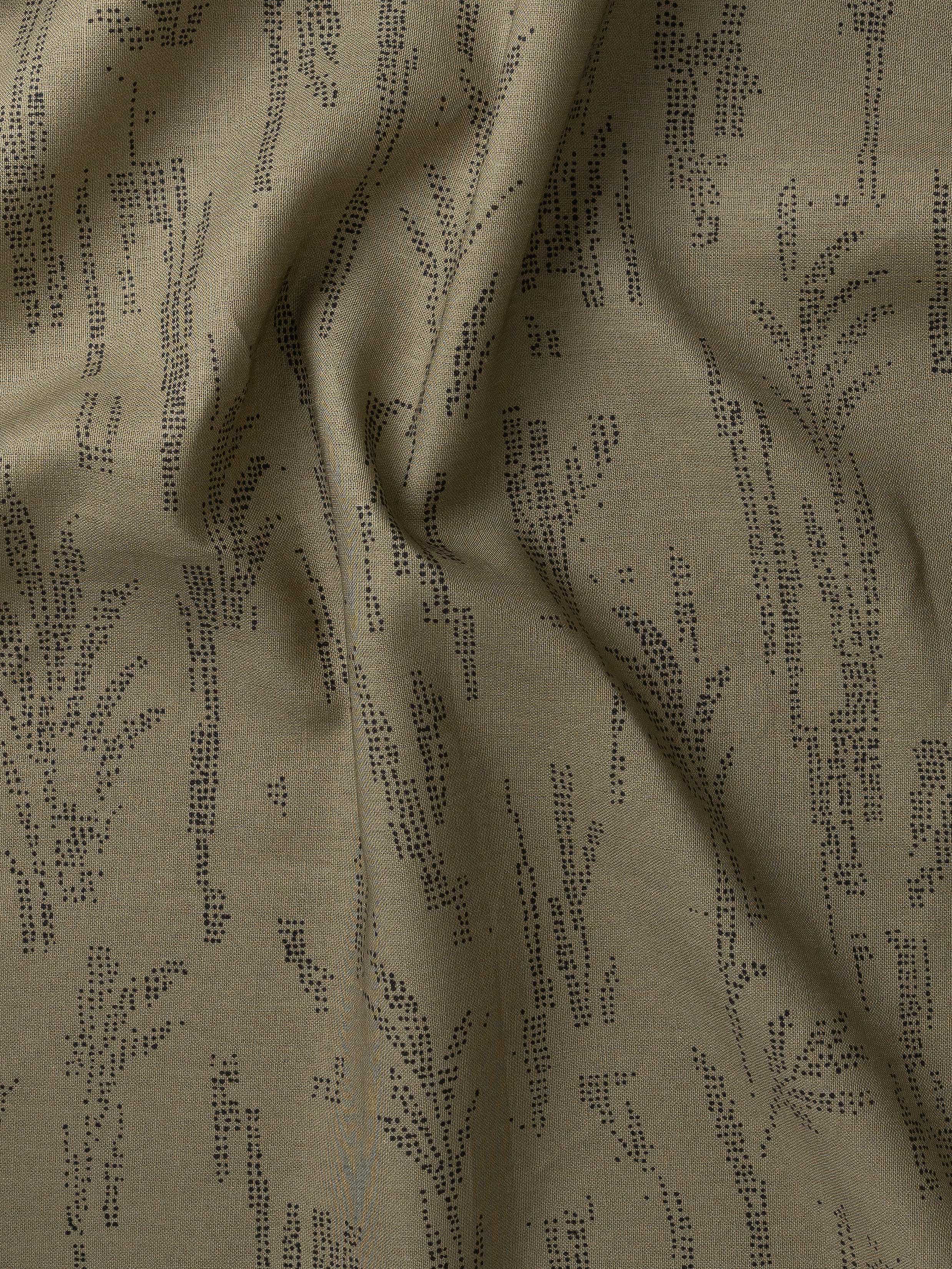 Detail of gently draped printed fabric with a black pointillist wheat frond pattern on a sage green background. 