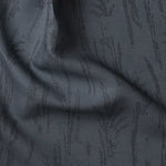 Detail of gently draped printed fabric with a black pointillist wheat frond pattern on a dark blue background. 