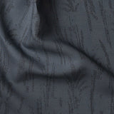 Detail of gently draped printed fabric with a black pointillist wheat frond pattern on a dark blue background. 