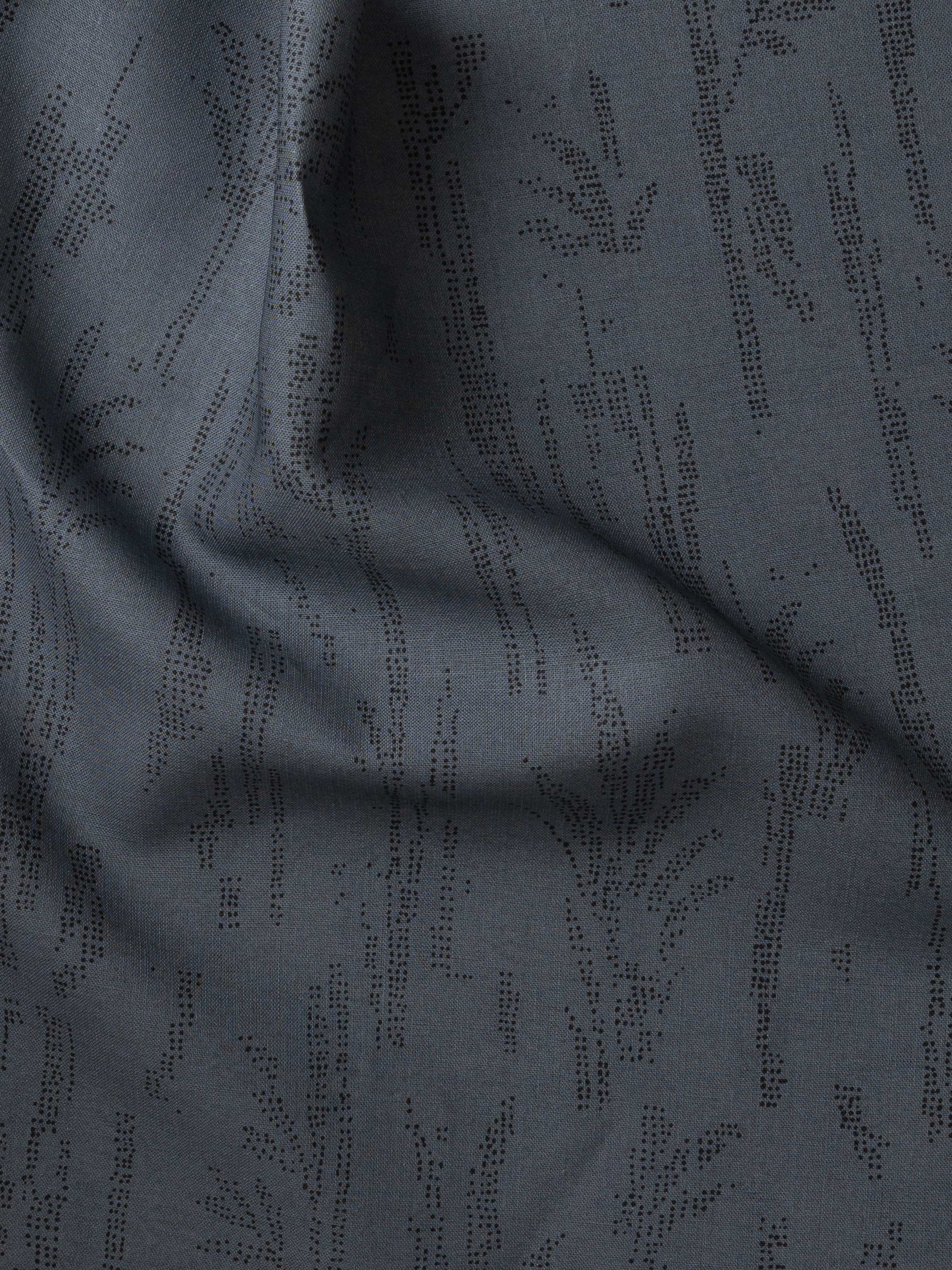 Detail of gently draped printed fabric with a black pointillist wheat frond pattern on a dark blue background. 
