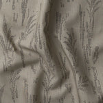Detail of gently draped printed fabric with a black pointillist wheat frond pattern on a taupe background. 