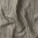 Detail of gently draped printed fabric with a black pointillist wheat frond pattern on a taupe background. 
