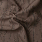 Detail of gently draped printed fabric with a black pointillist wheat frond pattern on a warm brown background. 