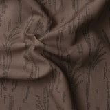 Detail of gently draped printed fabric with a black pointillist wheat frond pattern on a warm brown background. 