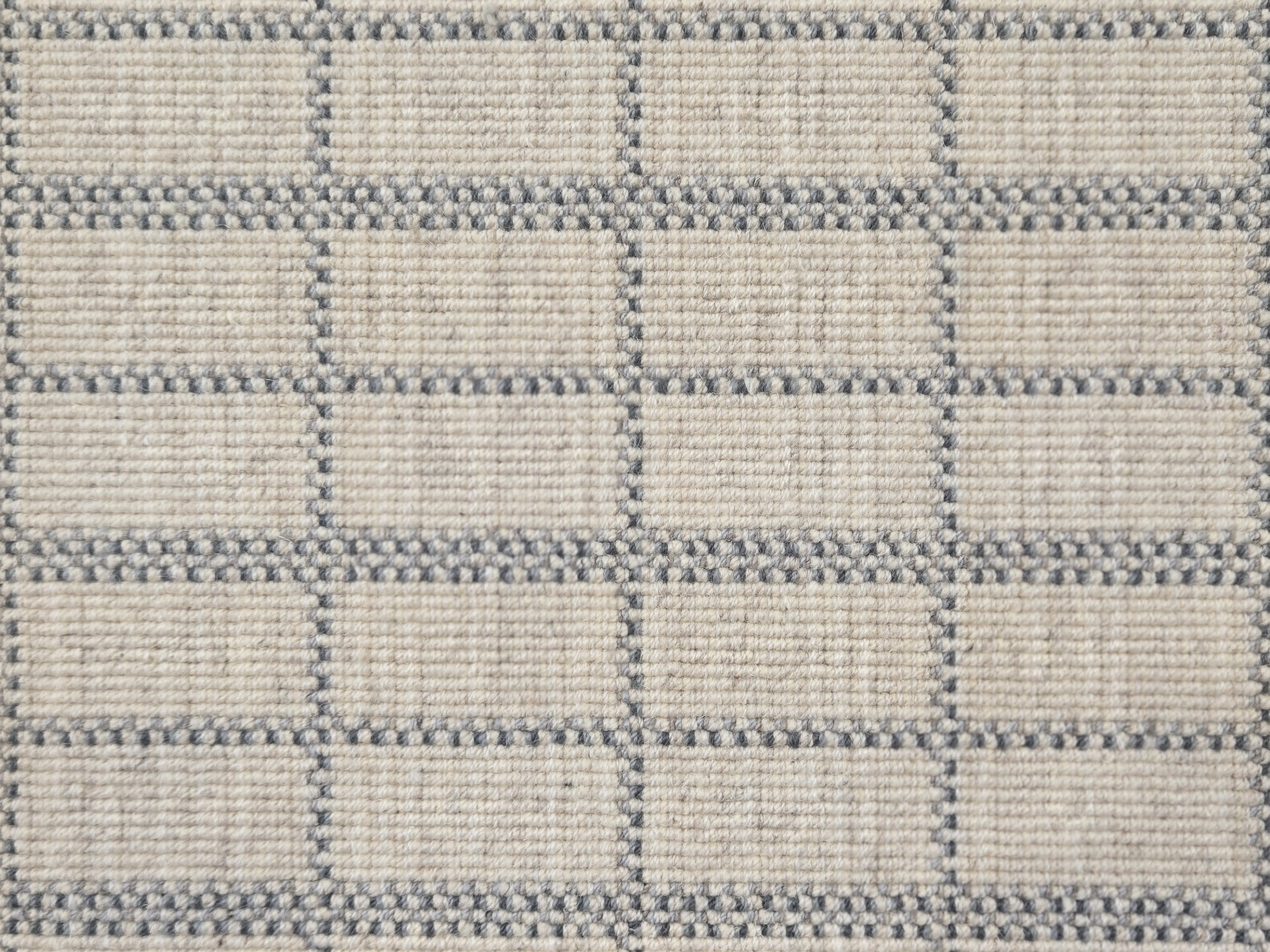 Broadloom carpet detail in plaid grid in shades of blue on a beige field.